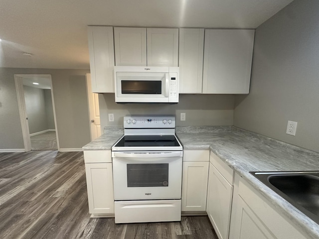 kitchen with light countertops, dark wood-type flooring, white cabinets, a sink, and white appliances