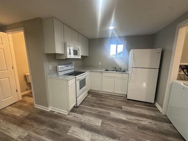 kitchen with white appliances, white cabinets, dark wood finished floors, light countertops, and a sink