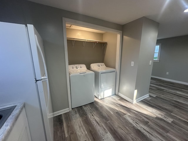 laundry room with laundry area, dark wood-type flooring, washer and clothes dryer, and baseboards