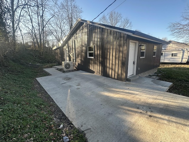 exterior space with board and batten siding, ac unit, and a patio area