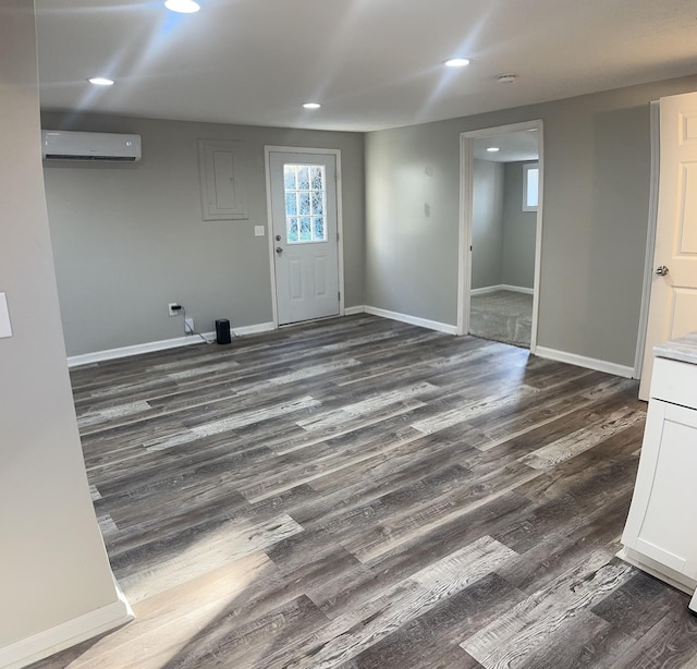 unfurnished room with dark wood-type flooring, recessed lighting, baseboards, and a wall mounted AC