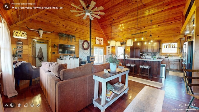 living room with wooden walls, wood ceiling, dark wood-type flooring, a wood stove, and high vaulted ceiling