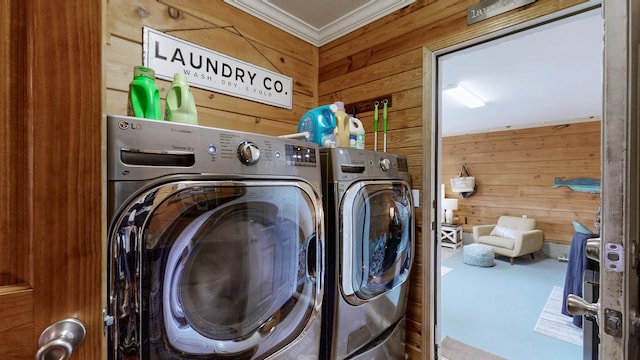 laundry area featuring crown molding, laundry area, wood walls, and washer and clothes dryer