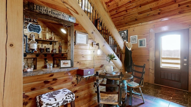 dining room featuring wooden ceiling, wood walls, stairway, and a dry bar