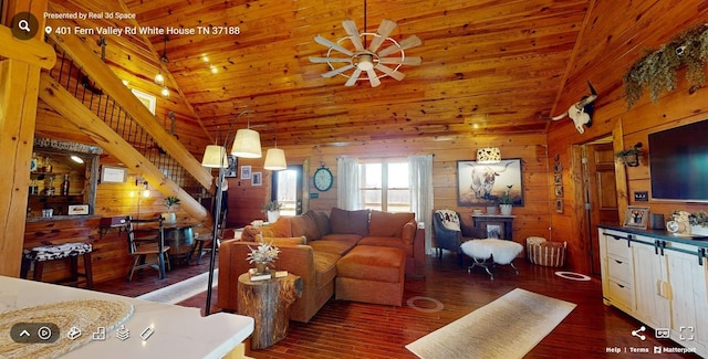 living room featuring wooden walls, ceiling fan, wood finished floors, stairs, and high vaulted ceiling