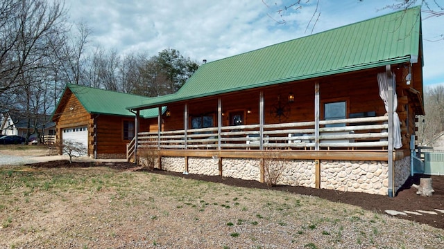 exterior space featuring a porch, central AC, metal roof, log siding, and a garage