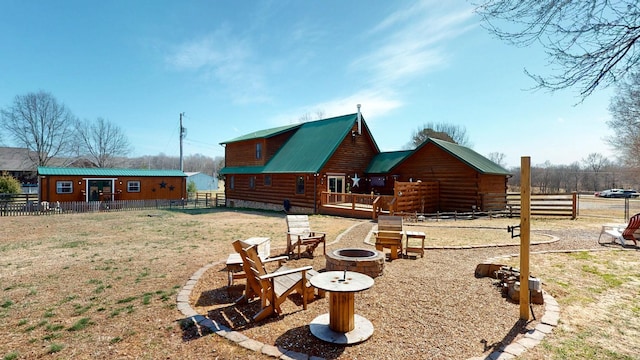 exterior space with metal roof, a fire pit, and fence