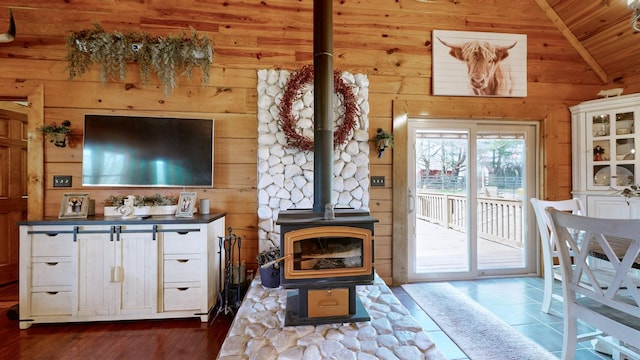 living area with a wood stove, wooden ceiling, wooden walls, and lofted ceiling