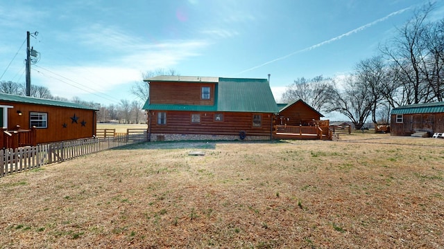 back of property featuring a yard, metal roof, a deck, and fence