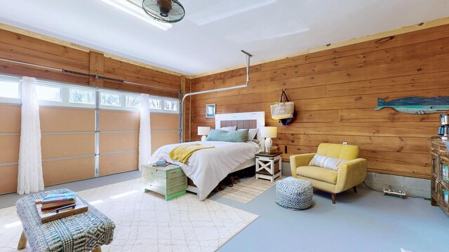 bedroom with a garage, wooden walls, and concrete flooring