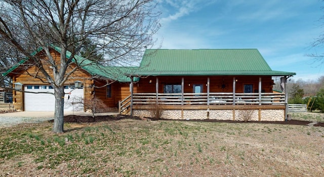 view of front of house with a garage, metal roof, covered porch, and log siding