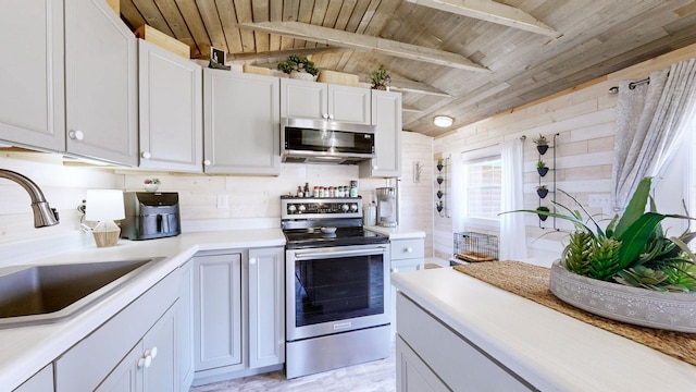 kitchen with wood ceiling, vaulted ceiling with beams, stainless steel appliances, light countertops, and a sink