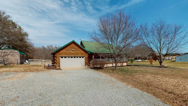 view of front facade featuring a garage, log siding, gravel driveway, fence, and a front lawn