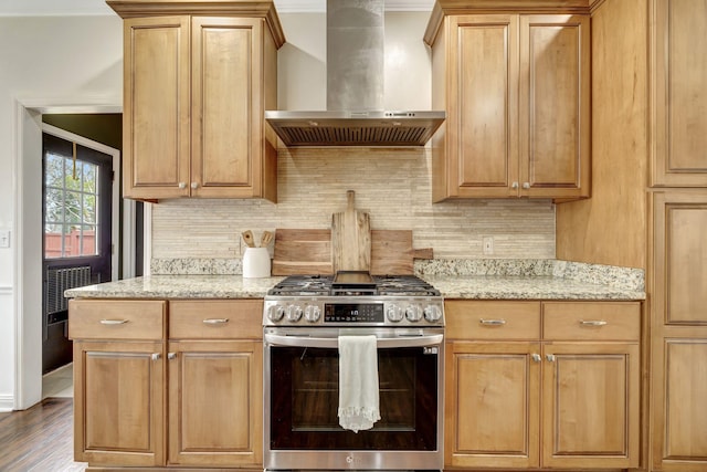 kitchen featuring light stone countertops, stainless steel gas range, wall chimney exhaust hood, and decorative backsplash