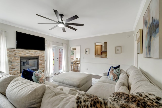 living room with baseboards, a ceiling fan, ornamental molding, french doors, and a fireplace