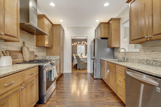 kitchen with appliances with stainless steel finishes, light stone countertops, crown molding, wall chimney range hood, and a sink