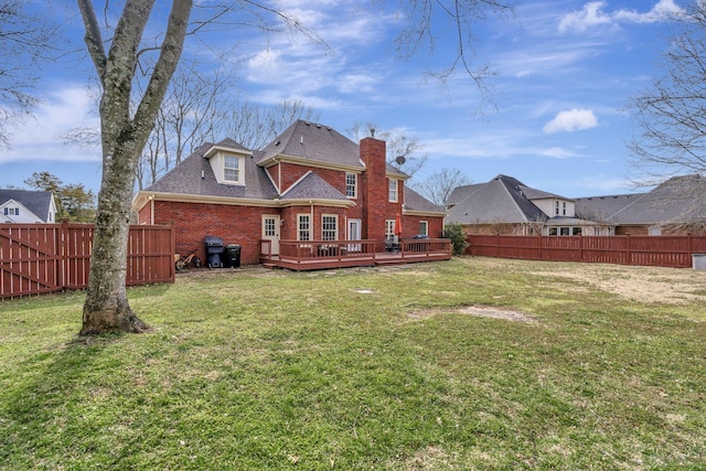 rear view of house with a deck, brick siding, a lawn, and a fenced backyard