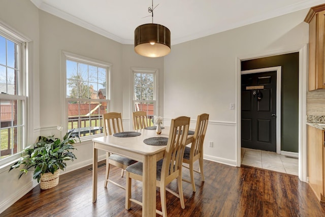 dining space featuring crown molding, baseboards, and wood finished floors