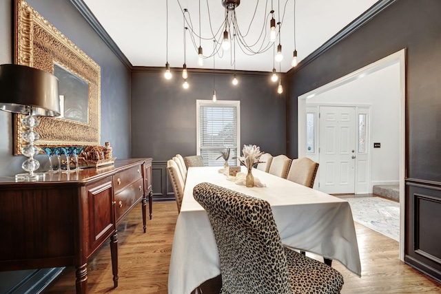 dining area with ornamental molding, light wood-style flooring, and a notable chandelier