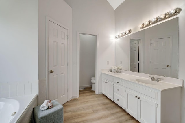 full bath with wood finished floors, a sink, toilet, and double vanity