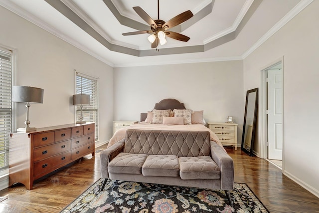 bedroom with crown molding, baseboards, a raised ceiling, and wood finished floors