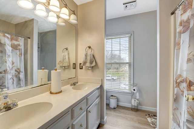 bathroom with double vanity, wood finished floors, a sink, and visible vents