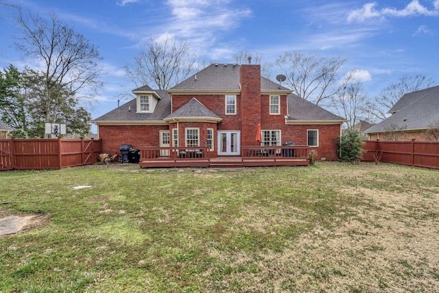 rear view of house with brick siding, a fenced backyard, a lawn, and a wooden deck