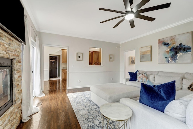 living area with ceiling fan, a fireplace, dark wood finished floors, and crown molding