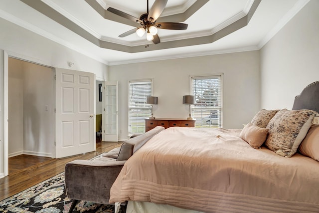 bedroom featuring ornamental molding, a raised ceiling, and wood finished floors