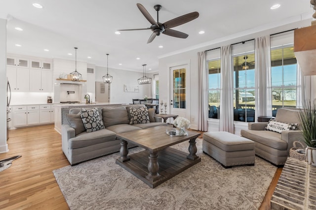 living room with light wood-style floors, ceiling fan, crown molding, and recessed lighting