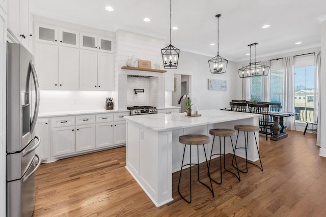 kitchen with a breakfast bar, a center island, white cabinetry, range, and stainless steel fridge with ice dispenser