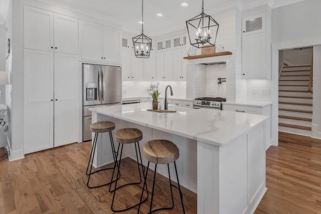 kitchen with stainless steel appliances, light wood-type flooring, white cabinets, and a sink