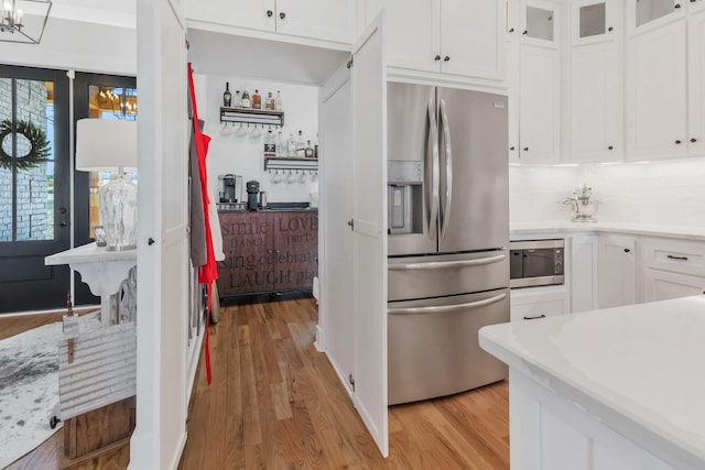 kitchen featuring stainless steel appliances, light countertops, light wood-style flooring, and white cabinetry