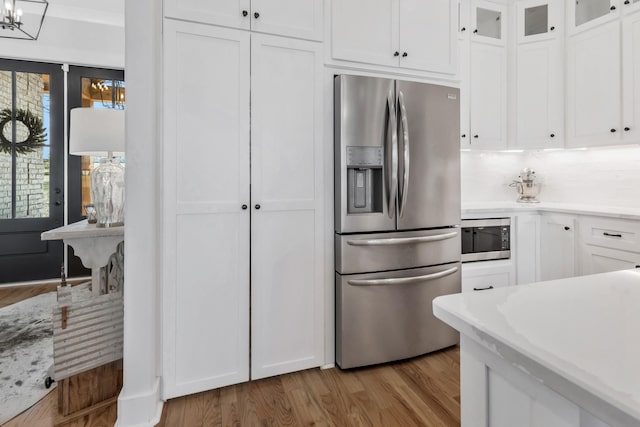 kitchen with light wood finished floors, appliances with stainless steel finishes, and white cabinetry