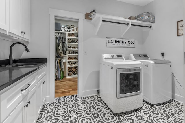 clothes washing area featuring a sink, baseboards, independent washer and dryer, cabinet space, and tile patterned floors