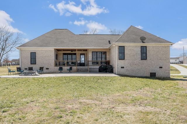 back of property with brick siding, a shingled roof, a lawn, crawl space, and a patio area