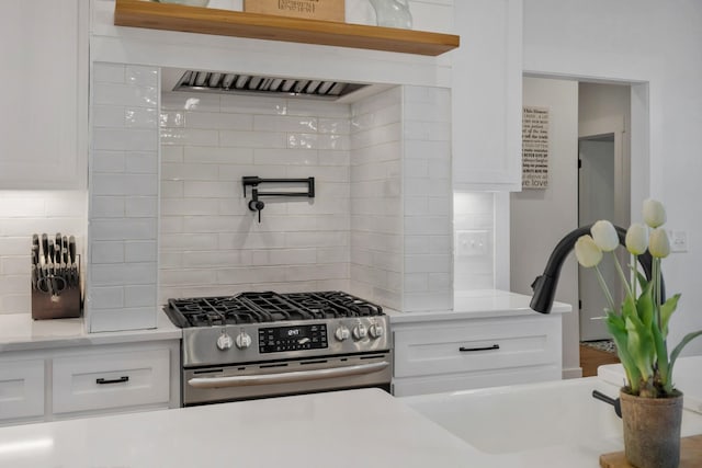 kitchen featuring light countertops, backsplash, stainless steel range with gas cooktop, and white cabinets