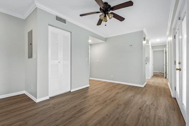 spare room featuring crown molding, visible vents, wood finished floors, electric panel, and baseboards