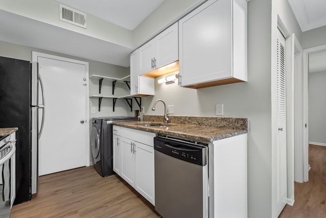 kitchen featuring stainless steel appliances, visible vents, white cabinets, a sink, and separate washer and dryer