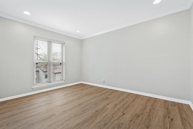 empty room featuring crown molding, wood finished floors, and baseboards