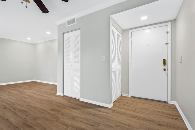 entrance foyer featuring visible vents, crown molding, baseboards, and wood finished floors