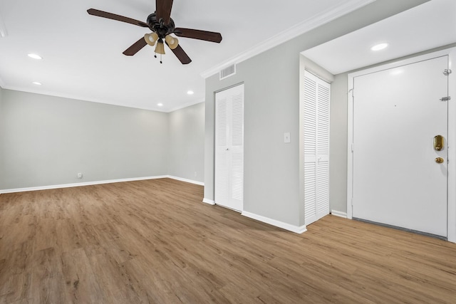 interior space featuring visible vents, baseboards, wood finished floors, crown molding, and recessed lighting