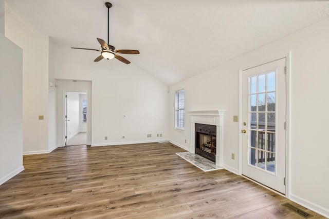 unfurnished living room with baseboards, visible vents, a ceiling fan, wood finished floors, and a fireplace