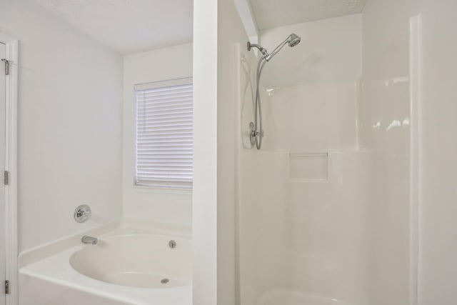 bathroom featuring a shower, a textured ceiling, and a bath