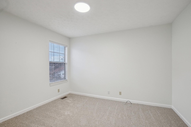 carpeted empty room featuring baseboards and visible vents