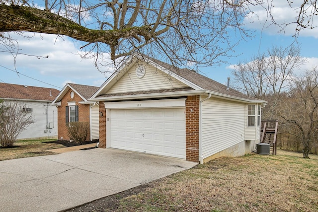 view of side of property with central AC, brick siding, a lawn, and concrete driveway