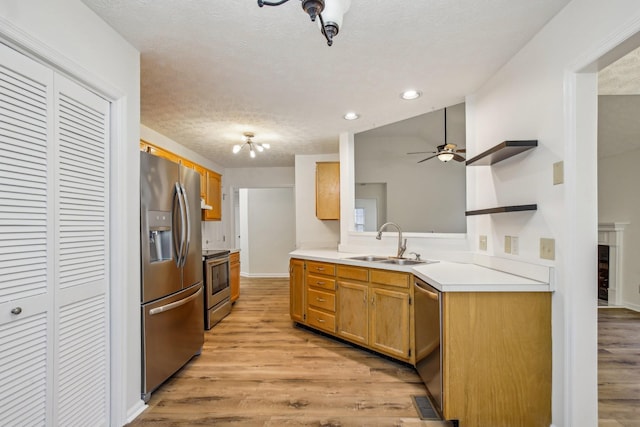 kitchen featuring open shelves, light wood-style flooring, stainless steel appliances, and a sink