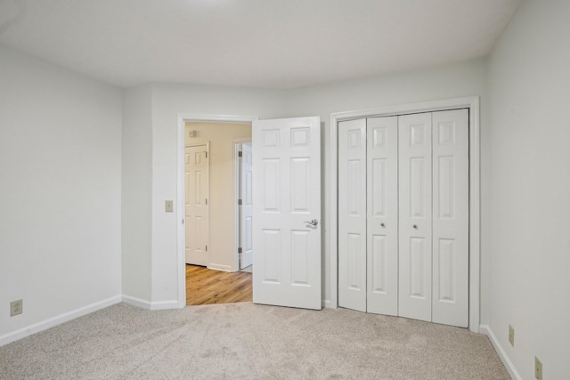 unfurnished bedroom featuring carpet, baseboards, and a closet