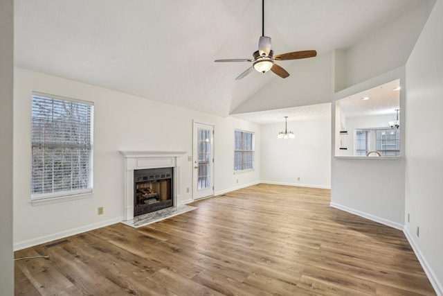 unfurnished living room with visible vents, a fireplace with flush hearth, wood finished floors, baseboards, and ceiling fan with notable chandelier