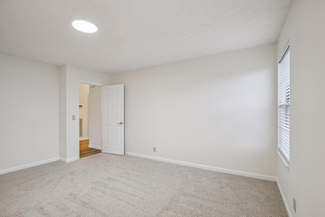 carpeted empty room featuring plenty of natural light and baseboards